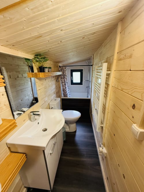 Salle de bains moderne du Lodge AZALÉE à Cabanes et lodges du Belvédère avec murs en bois, lavabo blanc, toilettes et sol foncé