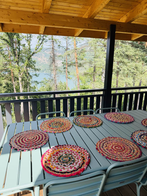 Terrasse de salle à manger extérieure du Lodge AZALÉE avec coussins de siège tissés colorés, poutres en bois, vues sur le lac et les montagnes