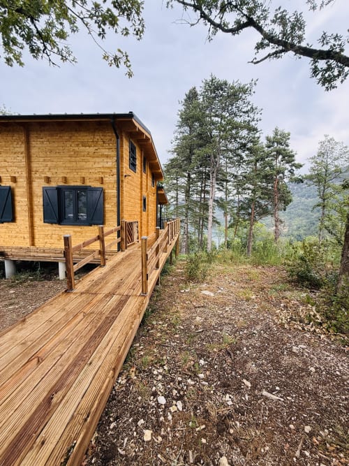 Chalet en bois avec terrasse dominant les montagnes boisées et la vallée du Ain aux Cabanes et lodges du Belvédère, Serrières-sur-Ain