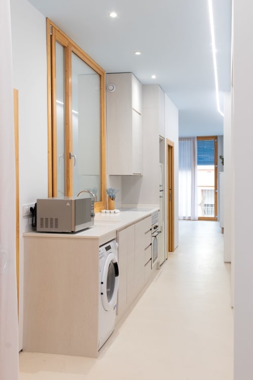 Moderna lavandería con lavadora, encimera y gran espejo en apartamento Ona vacaciones en el puerto de Gandía