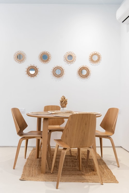 Comedor moderno con mesa y sillas de madera, espejos tejidos decorativos en la pared, apartamento en Gandía con vistas a la piscina