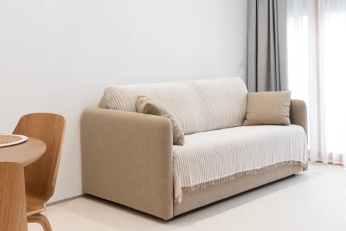Sofá moderno beige con manta rayada en luminoso apartamento de Ona Vacaciones, propiedad en puerto de Gandía