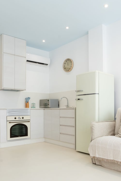 Cocina moderna en dúplex de Gandía con muebles claros, nevera crema y techo azul claro