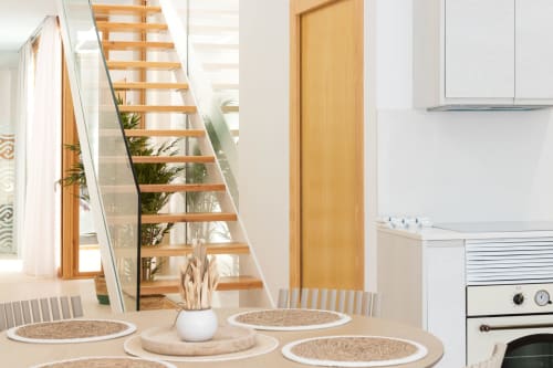 Comedor moderno en dúplex de Gandía con escaleras de madera, cocina blanca y vista a la piscina en Ona vacaciones