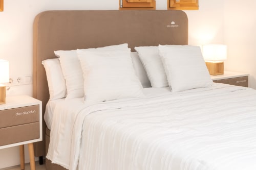 Habitación moderna en Ona vacaciones de Gandía con cabecero beige, ropa de cama blanca, mesitas de madera y vistas a la piscina