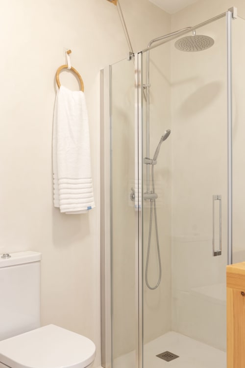 Baño moderno con ducha accesible, alcachofa de lluvia y toallero blanco en Ona vacaciones, Gandía