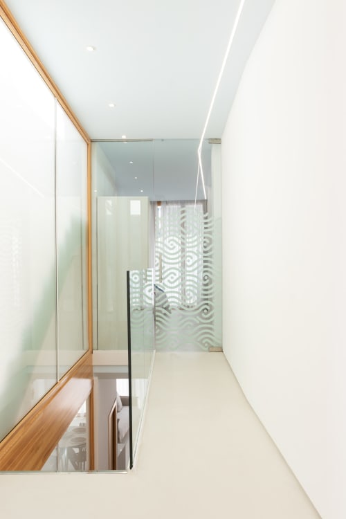 Pasaje moderno con estructura de madera y vidrio en el dúplex Ona vacaciones Gandía, con puertas de vidrio con patrón geométrico