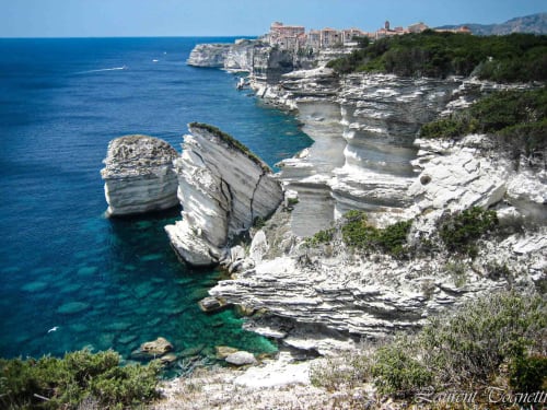 Falaises de calcaire blanc et mer Méditerranée turquoise près de Propriano, Corse avec village perché