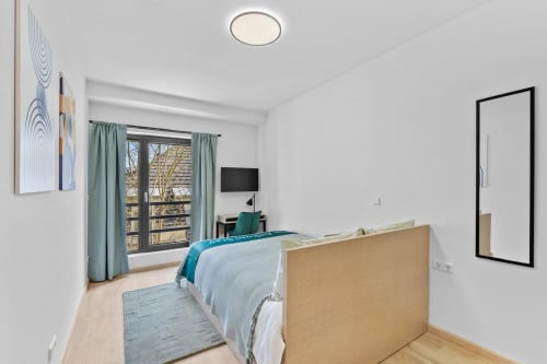 Modern bedroom at Mattbnb Metz with queen bed, city view balcony, TV, and contemporary design
