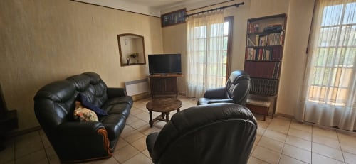 Spacieux séjour de la villa Mi Casa Es Su Casa à Carcassonne avec sièges en cuir noir, TV, bibliothèque et vue sur la ville