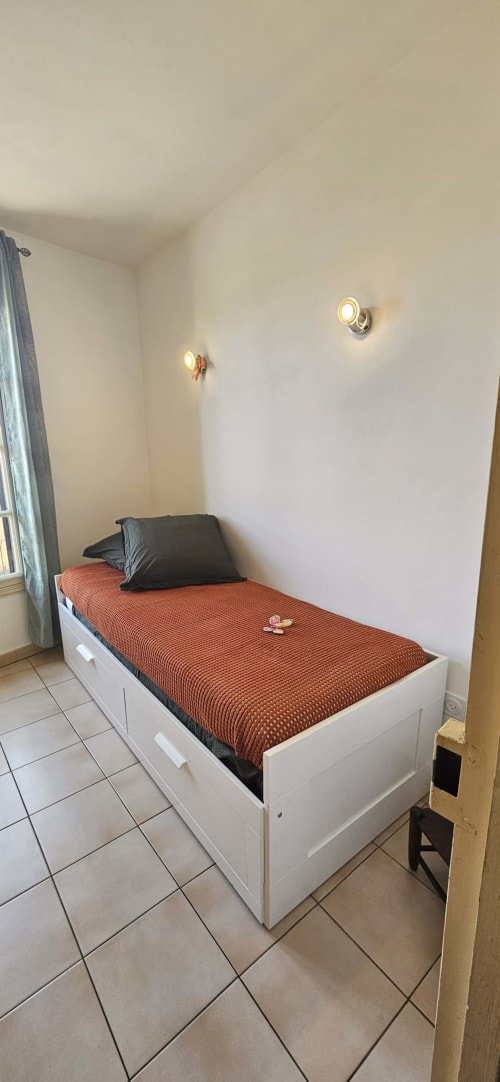 Chambre lumineuse avec un lit simple aux draps orange à la villa Mi Casa Es Su Casa, Carcassonne