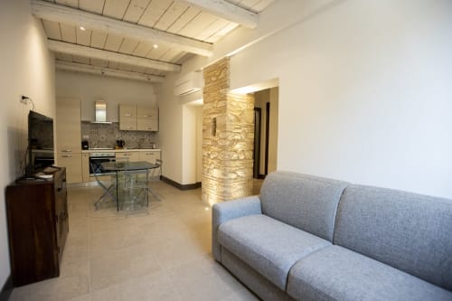 Moderno appartamento a Norcia con divano grigio, zona cucina e colonna in pietra