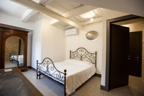 Ampia camera da letto a Le Mura Rooms a Norcia con letto in ferro battuto ornamentale, specchio e armadio in legno