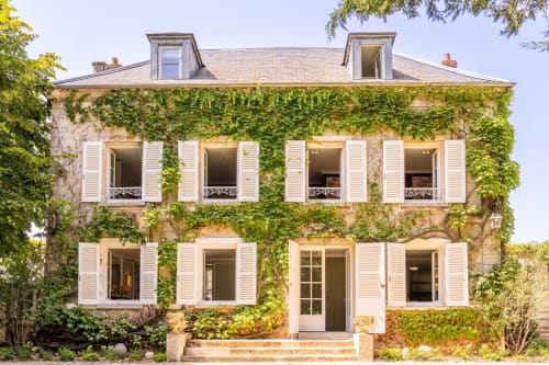 Ivy-covered stone manor house with white shutters and mansard roof at Le Domaine by A&G in Vendrest, France