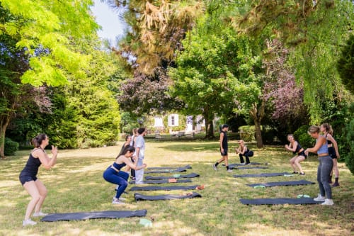 Cours de fitness en plein air sur les jardins entretenus du Domaine by A&G à Vendrest, avec arbres d'ombrage et cadre champêtre