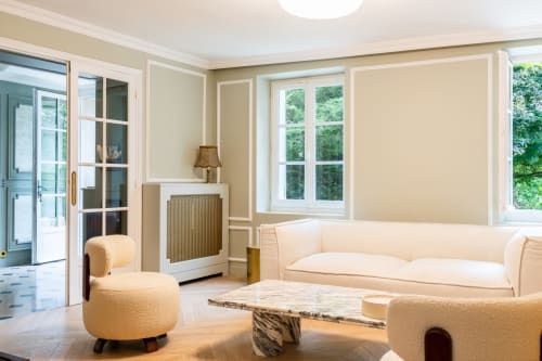 Salon élégant du cottage Le Domaine by A&G à Vendrest, avec mobilier crème, cheminée et vue sur le jardin