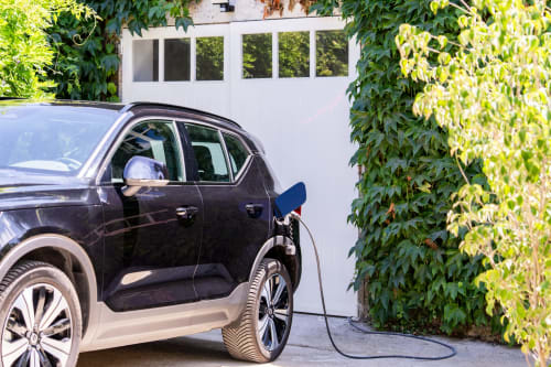 Recharge de véhicule électrique au domaine by A&G cottage à Vendrest, avec murs couverts de lierre et façade blanche.