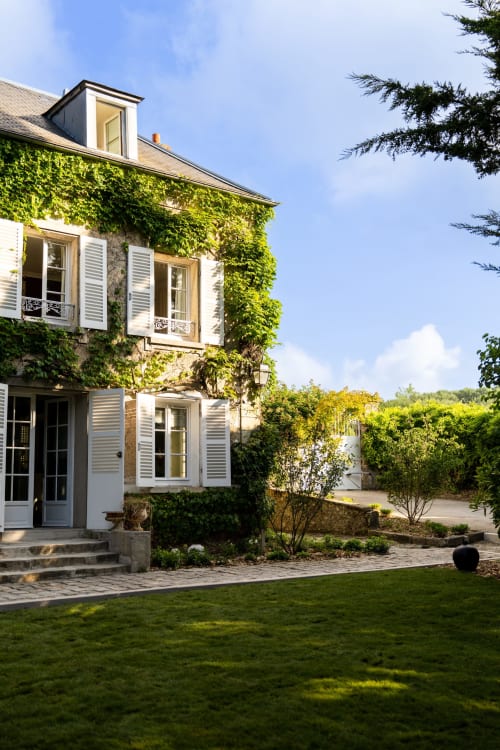 Manoir français couvert de lierre au Domaine by A&G à Vendrest, aux volets blancs, pelouse soignée et cour de jardin