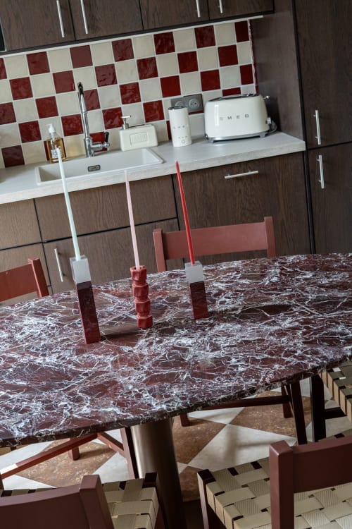 Salle à manger contemporaine de la Villa DeauvHills 2 avec table en marbre, chaises rouges et cuisine moderne au dosseret géométrique