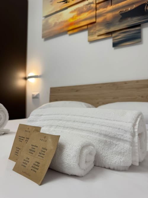Asciugamani bianchi arrotolati con biglietto di benvenuto sul letto della camera Cleopatra al Queen Hotel di Campofilone