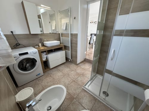 Moderno bagno dell'appartamento Anastasia al Queen Hotel Campofilone con lavatrice, lavabo, doccia e scaldasalviette