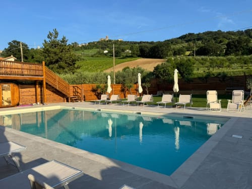 Lussuosa piscina resort con lettini e ombrelloni con vista sulle dolci colline della Toscana, Campofilone Italia