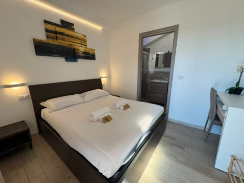 Camera moderna con letto nero, biancheria bianca, bagno en-suite e opere paesaggistiche nella stanza Sissi del Queen Hotel, Campofilone