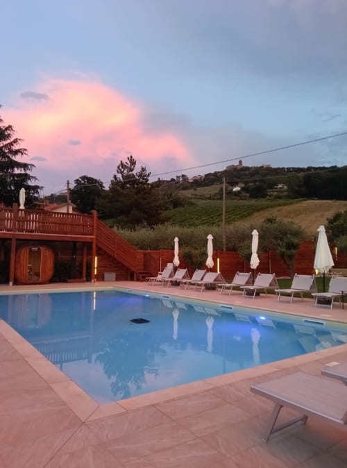 Tramonto presso la piscina del Queen Hotel a Campofilone, Italia, con lettini e vista sulla campagna