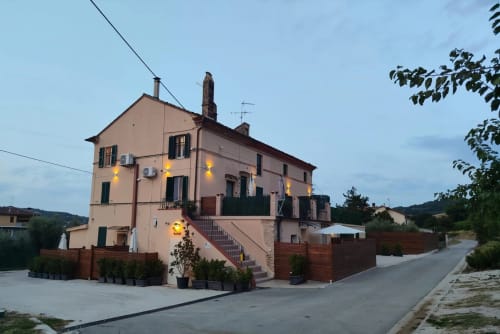 Esterno dell'Hotel Queen al tramonto a Campofilone, Italia - edificio rosa con ingresso illuminato e cancellata in legno