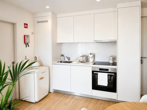 Cozinha moderna e branca no apartamento Terra Clara Studios, Esposende, com eletrodomésticos em aço inoxidável e backsplash em mármore