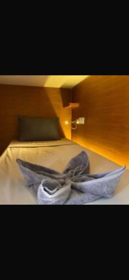 Single bed with gray pillows in female dormitory room at Kaniu Lombok Hostel, Kuta with warm lighting