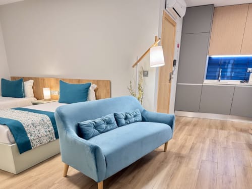 Quarto moderno no RIA CENTRUM em Aveiro com sofá azul, camas de solteiro, cabeceira de madeira e móveis contemporâneos