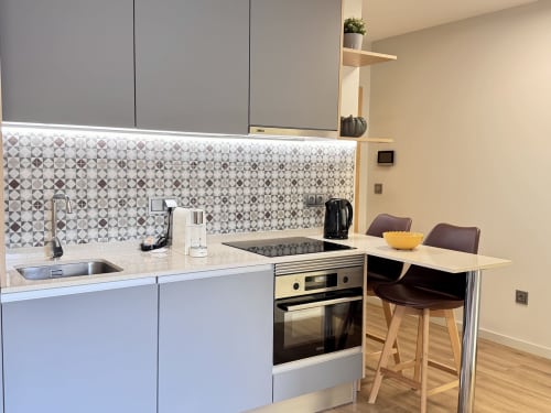 Cuisine moderne au RIA CENTRUM Smart Residence, Aveiro. Armoires blanches, cuisinière à induction, dosseret carrelé, coin repas