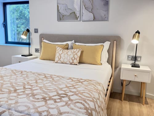 Chambre moderne au RIA CENTRUM Smart Residence, Aveiro avec tête de lit grise, oreillers jaunes, lampe de bureau et vue sur la ville