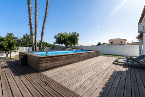 Luxury villa pool deck with wooden terrace, private swimming pool, and palm trees in Lagoa, Portugal