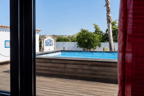 Piscina privada com água azul na villa Quinta do Águas em Lagoa, Portugal, vista do terraço com palmeira e branco