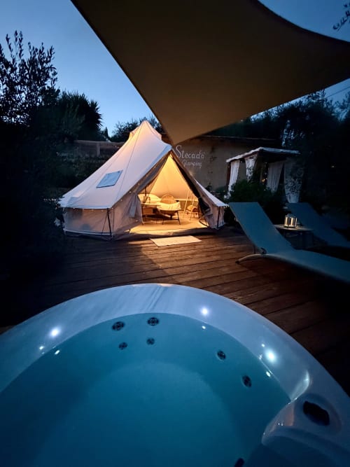 Agritusmo Stecadò glamping tent glowing at dusk with illuminated hot tub in foreground, Dolceacqua