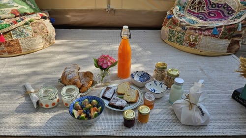 Breakfast spread in Tenda Uliveto at Agritusmo Stecadò, Dolceacqua featuring fresh pastries, fruit bowl, bread, jams, orange