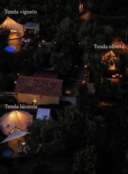 Aerial night view of Agritusmo Stecadò glamping tents in Dolceacqua garden with warm lighting