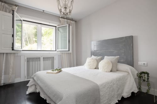 Dormitorio luminoso con ropa de cama blanca, cabecero gris y vistas a la montaña en la casa rural Vilaboa de Pontevedra