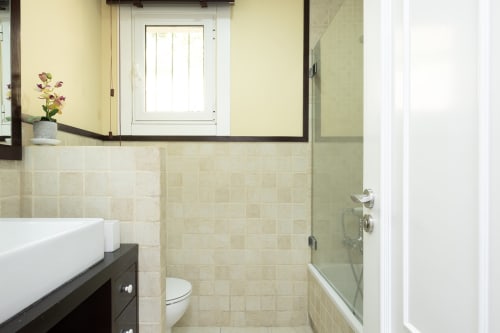 Baño moderno con lavamanos blanco tipo vessel, tocador oscuro y ducha en la casa Vilaboa de Bahía Rental, Pontevedra