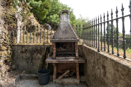 Rústica parrilla de piedra con verja de hierro forjado en jardín de cabaña, Vilaboa, Pontevedra