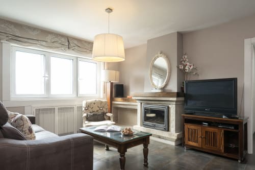 Elegante sala de estar con chimenea, TV de pantalla plana e iluminación colgante en la casa rural Vilaboa de Pontevedra