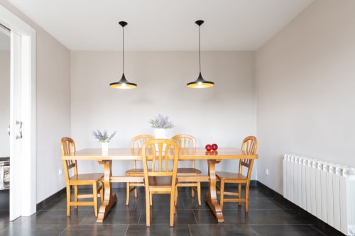 Comedor moderno de la casa rural Bahía con mesa de madera, sillas y lámparas colgantes negras en Pontevedra