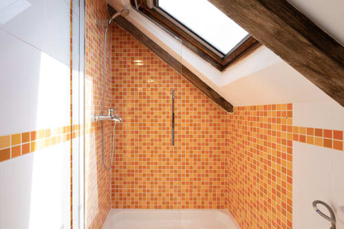 Baño moderno con azulejos de mosaico naranja en la casita Vilaboa de Bahía Rental, Pontevedra