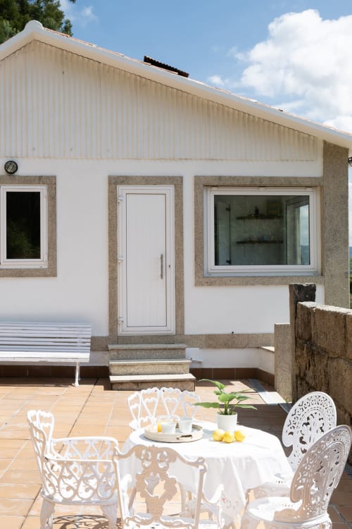 Terraza de cabaña en Bahía Rental con muebles blancos, mesa servida y vistas a la montaña en Pontevedra