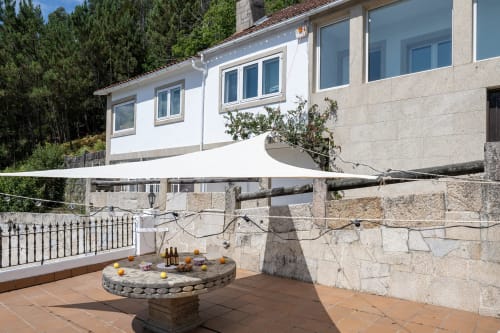 Terraza de la casita Vilaboa en Bahía Rental con vistas montañosas, muro de piedra, vela parasol blanca y mesa de comedor exterior