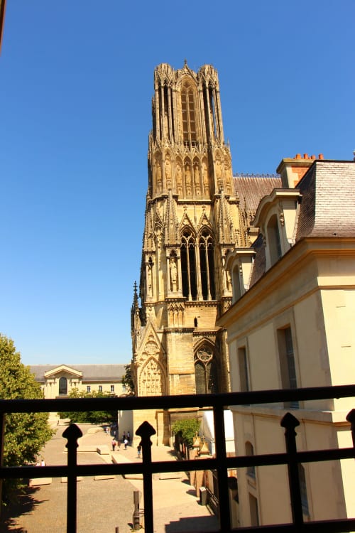 Reims Cathedral tower view from Le Cardinal apartment at Secrets de Chef de Cave hotel, clear blue sky