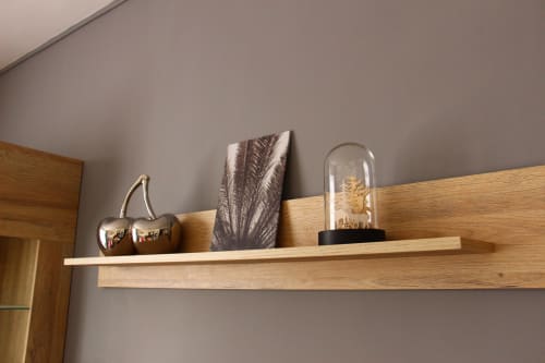 Wooden wall shelf in Le Cardinal apartment displaying decorative items including a metallic cherry figurine and glass dome