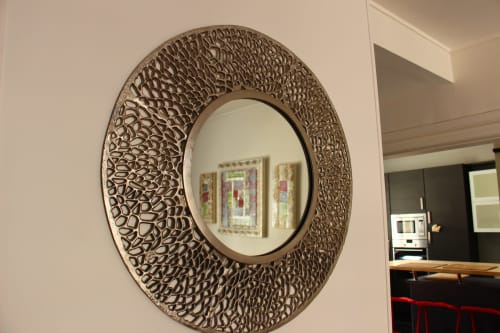 Ornate circular mirror with textured bronze frame hanging in Le Cardinal apartment at Secrets de Chef de Cave hotel in Reims